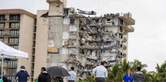 Partially collapsed beachfront apartment building with onlookers