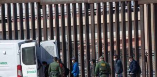 Trump Slams Brakes On ICE Rumor Border agents escort a group near a tall fence and a patrol van