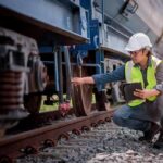 Railway inspector checking freight train wheel with tablet