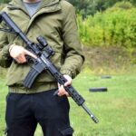 person holding a black rifle outdoors