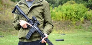 person holding a black rifle outdoors