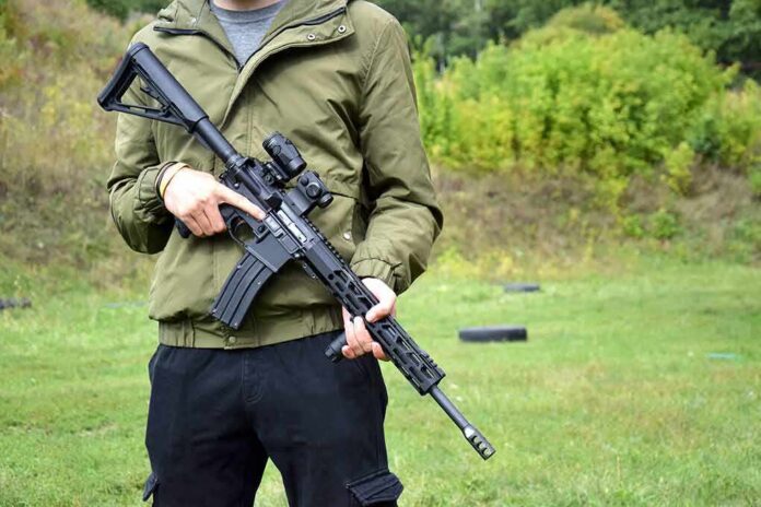 shutterstock_2107982456 person holding a black rifle outdoors