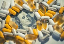 pills and capsules scattered over a hundred-dollar bill