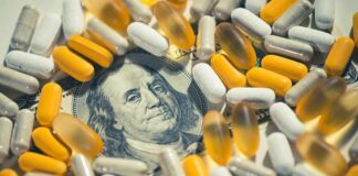 Medicare For All – With A Catch pills and capsules scattered over a hundred-dollar bill