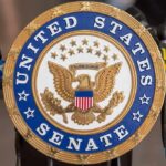 Last-Minute Flip Splits Democrats Wide Open United States Senate seal at a podium