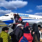 Haiti Receives First Major Deportation Flight Passengers boarding a commercial airplane via mobile stairs