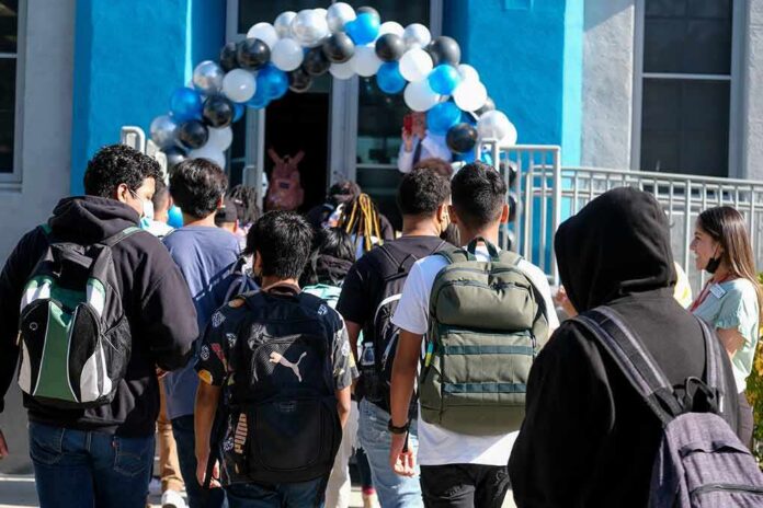 shutterstock_2190331653 Students with backpacks enter a school under a balloon arch