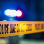 Police tape with blurred flashing lights in background