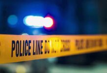 Police tape with blurred flashing lights in background