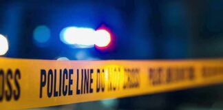 Police tape with blurred flashing lights in background