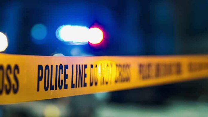 Police tape with blurred flashing lights in background
