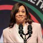 Kamala’s $20K VIP Night Sparks Fury woman at podium with two microphones