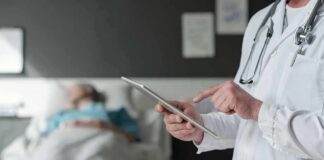 Doctor using tablet beside hospital patient