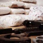 Piles of bagged powder with a handgun on a table