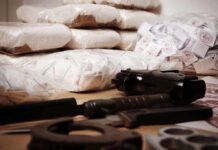 Piles of bagged powder with a handgun on a table