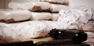 Piles of bagged powder with a handgun on a table
