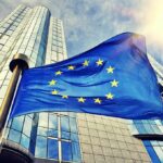 European Union flag waving in front of modern glass office buildings