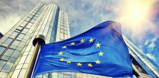 European Union flag waving in front of modern glass office buildings
