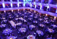 Ballroom filled with round tables at a formal gala dinner
