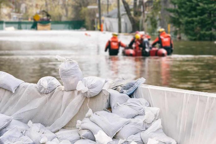 Sandbags stacked near a flooded street with rescue workers in a boat
