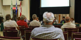 Election Heat: Mayor Lunges At Critic Audience members seated facing a presentation screen