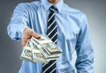 Person in business attire offering bundles of US dollar bills