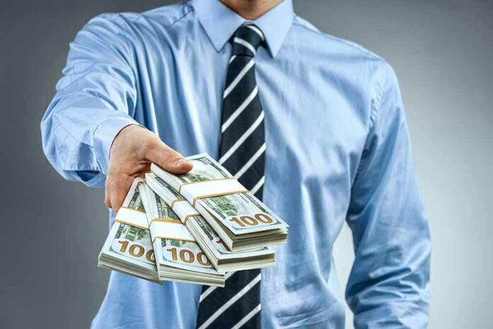Person in business attire offering bundles of US dollar bills