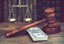 Wellness Check Uncovers Grisly Scam Judge's gavel beside cash and scales of justice on a wooden desk