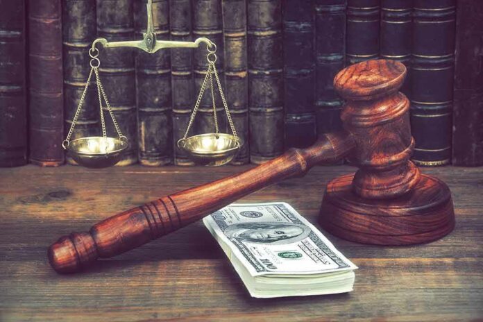 shutterstock_1037850442 Judge's gavel beside cash and scales of justice on a wooden desk