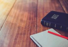 Christian Voters Focus on These 4 Issues Bible and notebook with red pencil on wooden table