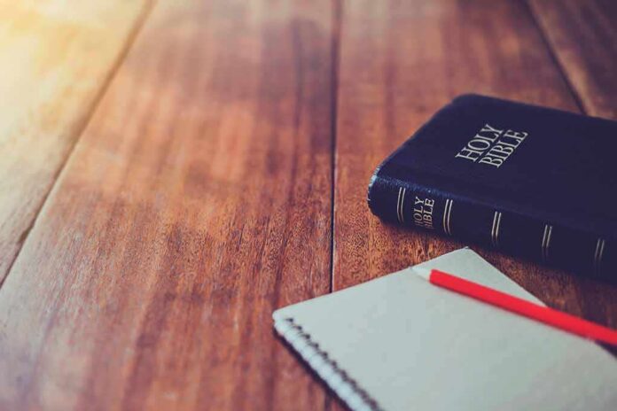 shutterstock_1070064413 Bible and notebook with red pencil on wooden table
