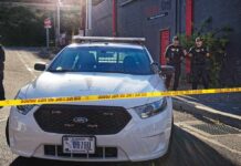 Aaron Guiel near police car behind yellow caution tape