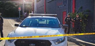 Aaron Guiel near police car behind yellow caution tape