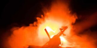 Toy helicopter silhouette against fiery explosion at night