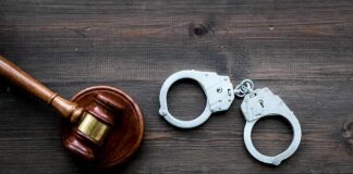 Supreme Court Whiplash Throws Man Back Judge's gavel and metal handcuffs on wooden table