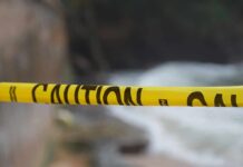 Yellow caution tape stretched across a blurred outdoor scene