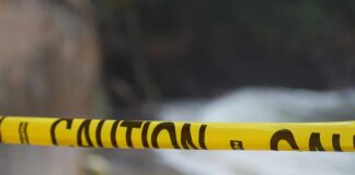 Yellow caution tape stretched across a blurred outdoor scene