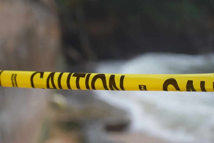 Yellow caution tape stretched across a blurred outdoor scene