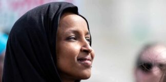 Comer Targets Omar’s Wild Asset Jump Ilhan Omar in profile wearing a black headscarf outdoors