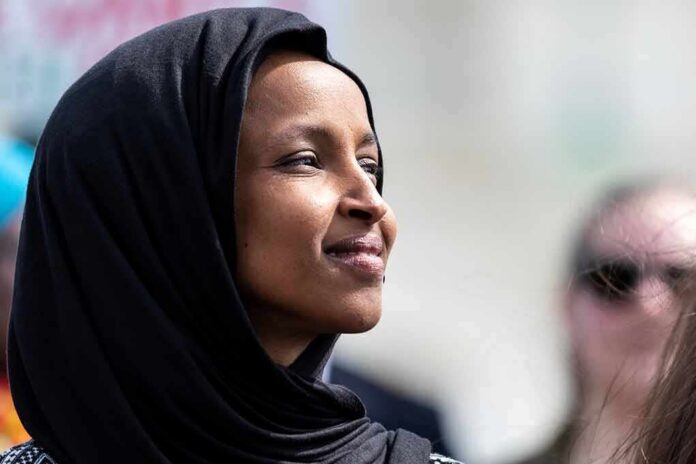 Ilhan Omar in profile wearing a black headscarf outdoors