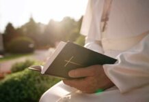 New Report Exposes Decades Of Abuse Person in white robe holding a Bible outdoors