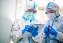 Plague Scare Deepens After Lab Death Two healthcare workers in full PPE reviewing a clipboard