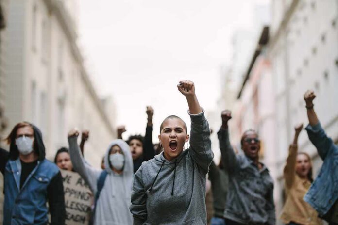 protester with raised fist leading a crowd in a city street