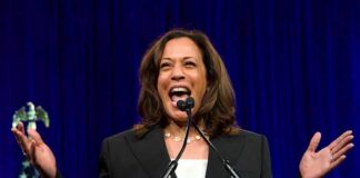 Crickets After Harris Flubbed Line Kamala Harris speaking at a podium with arms raised