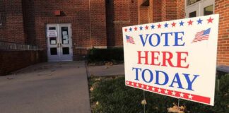 Voting sign outside a brick building entrance