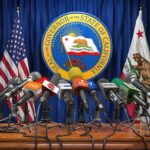 Press microphones at a podium before California governor seal