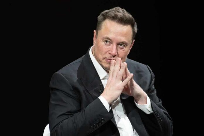 shutterstock_2318800287 Elon Musk seated in a dark setting with hands steepled near his face