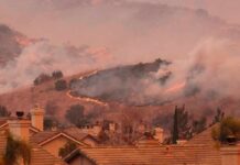 Wildfire burns on hillside near suburban homes